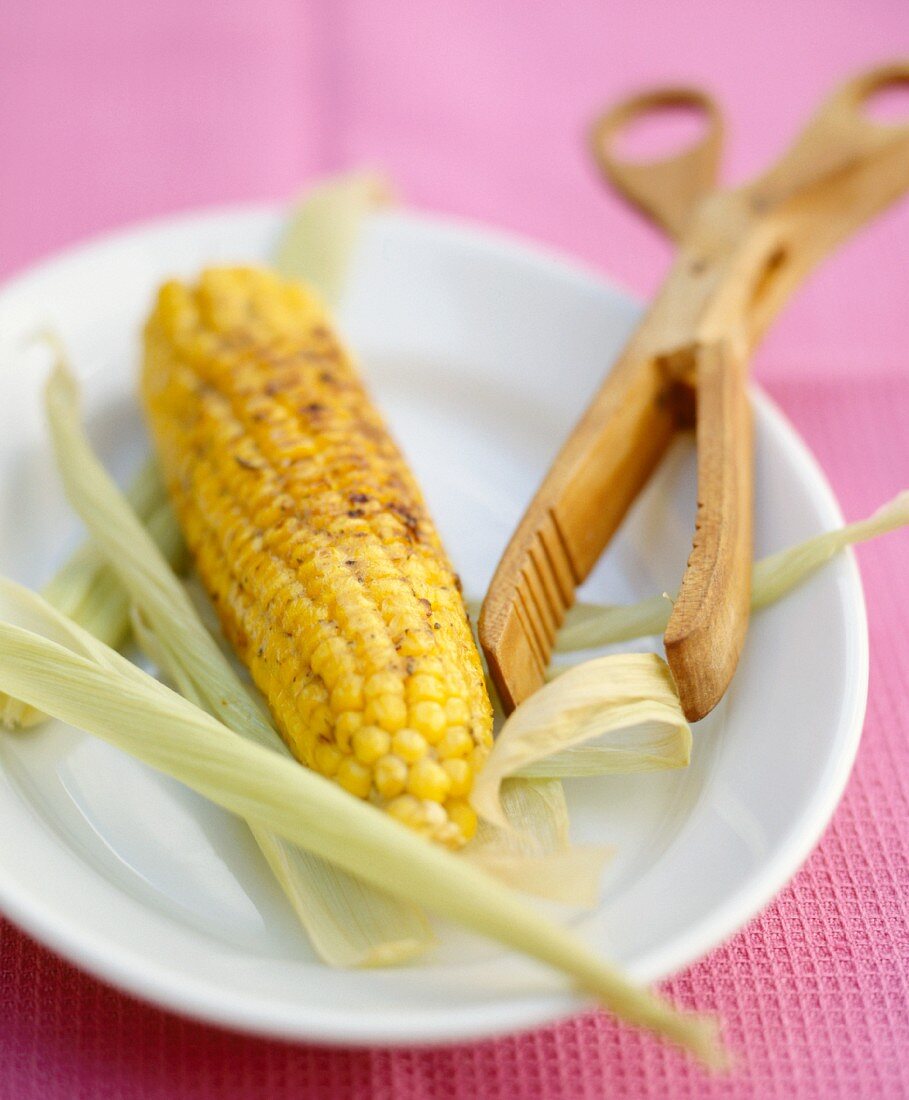 Gegrillter Maiskolben mit Holzzange