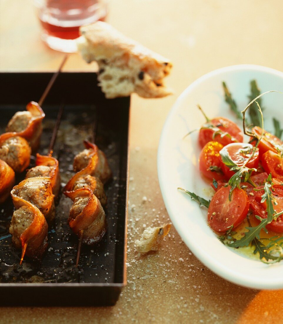 Meatball skewers with bacon, and a tomato and rocket salad