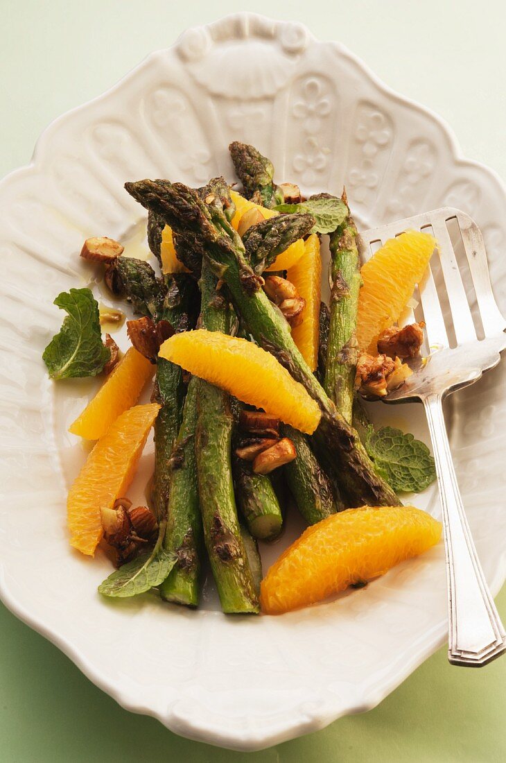 Green asparagus with orange segments and nuts