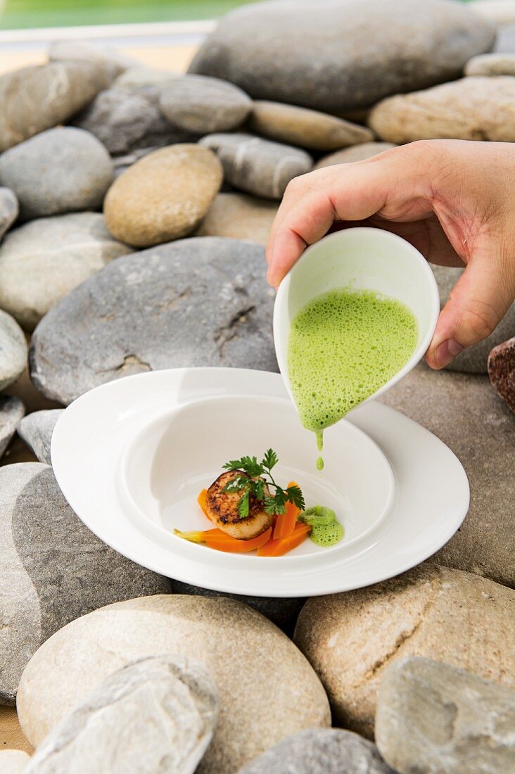 Watercress foam soup with a scallop and carrots