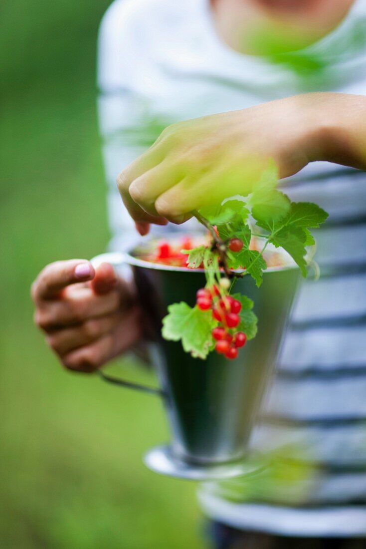 Girl holding mug with red currants twig