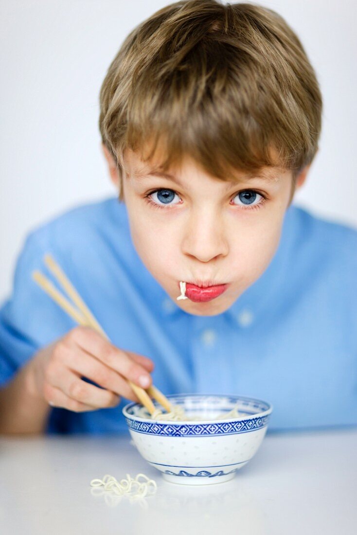Portrait of boy eating noodles with chopsticks