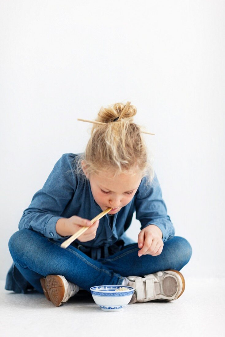 Mädchen isst mit Stäbchen