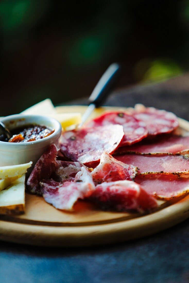 Schinken, Salami und Käse, in Scheiben geschnitten, auf Holzteller