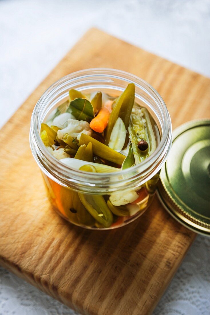 Vegetables pickled in vinegar, in an open screw-top jar