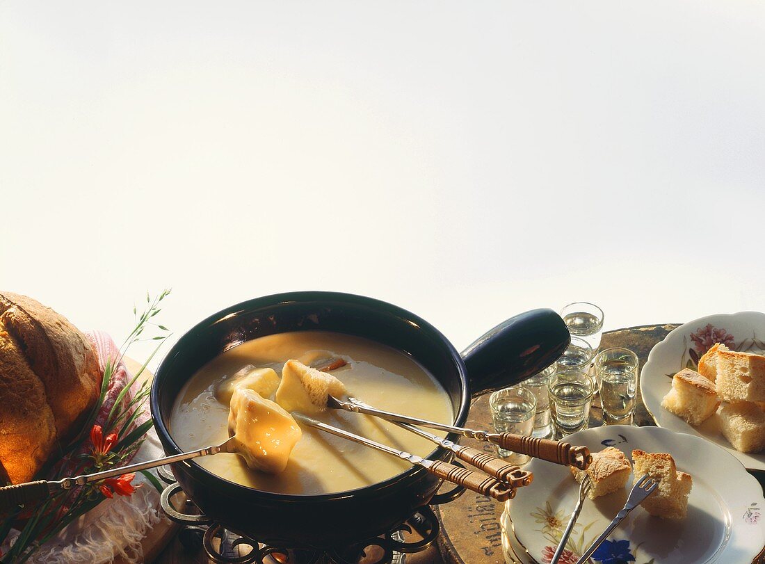 Käsefondue: Fonduetopf mit geschmolzenem Käse auf Rechaud