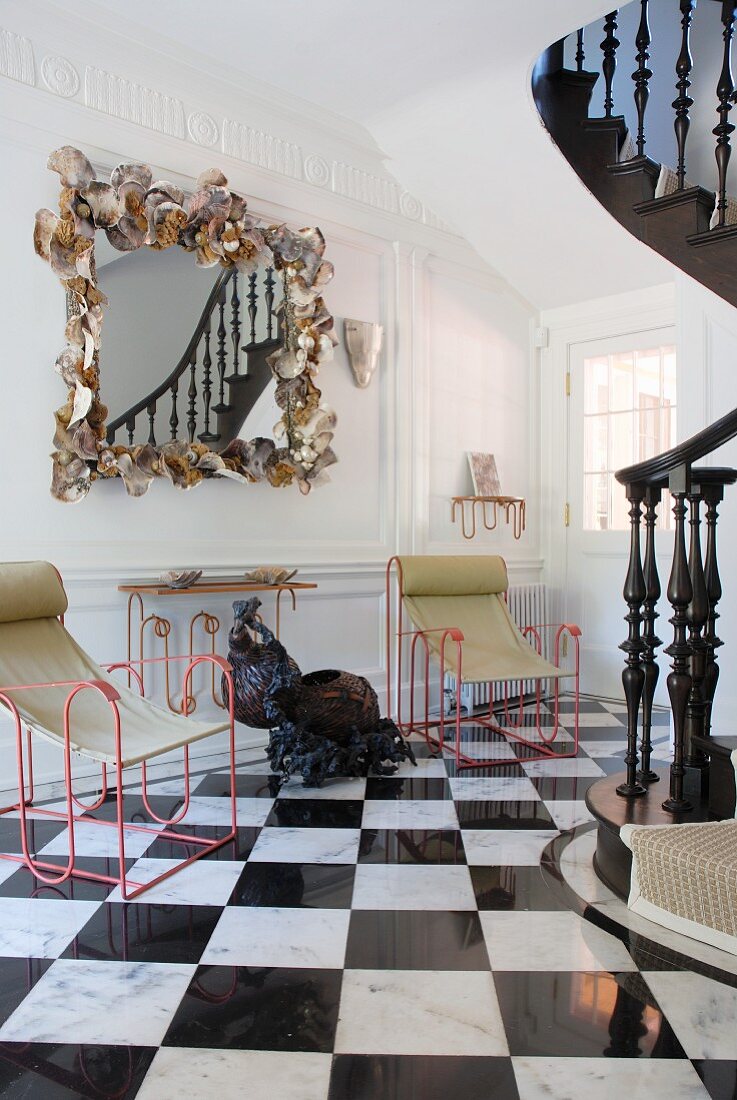 Postmodern, framed mirror and metal chairs with fabric seats in hallway with black and white, chequered marble tiles