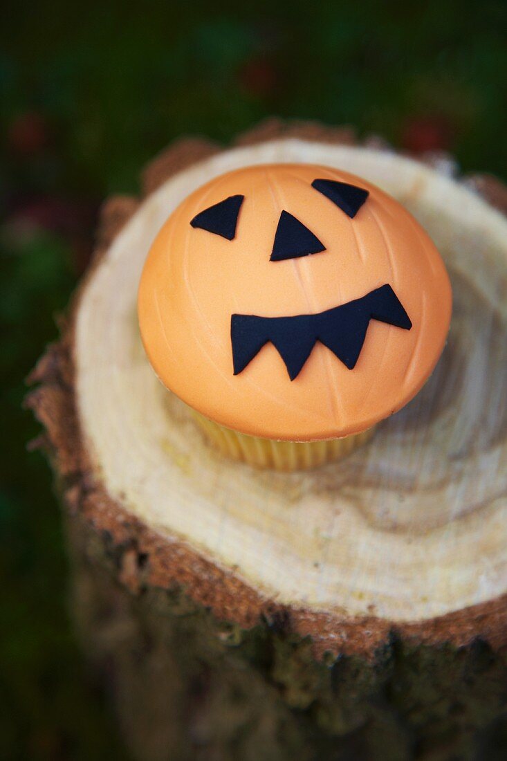 Cupcake decorated with a jack-o'-lantern face for Halloween
