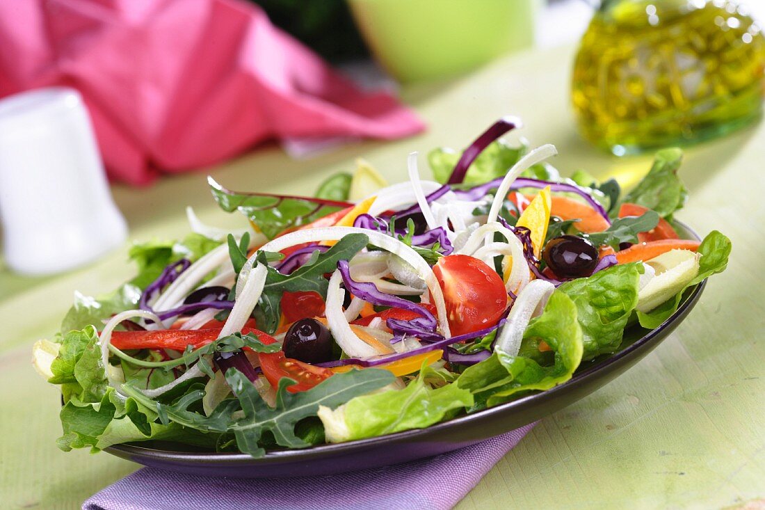 Mixed salad leaves with sliced vegetables, tomatoes and olives