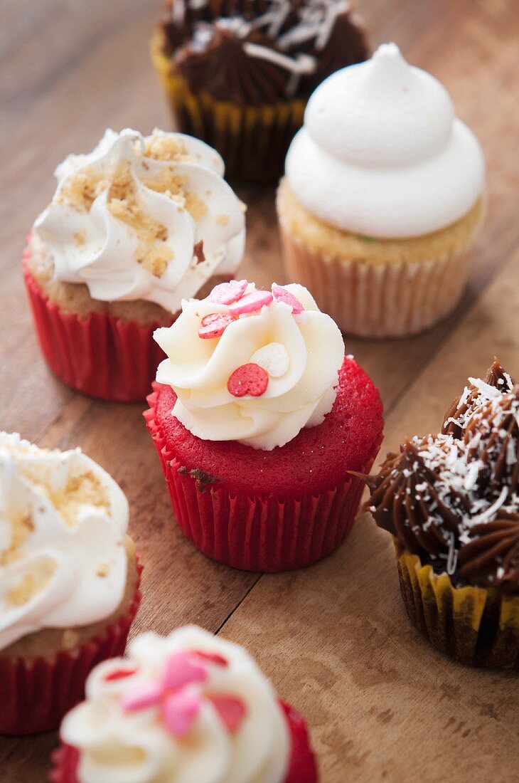 Assorted mini cupcakes on a wooden surface
