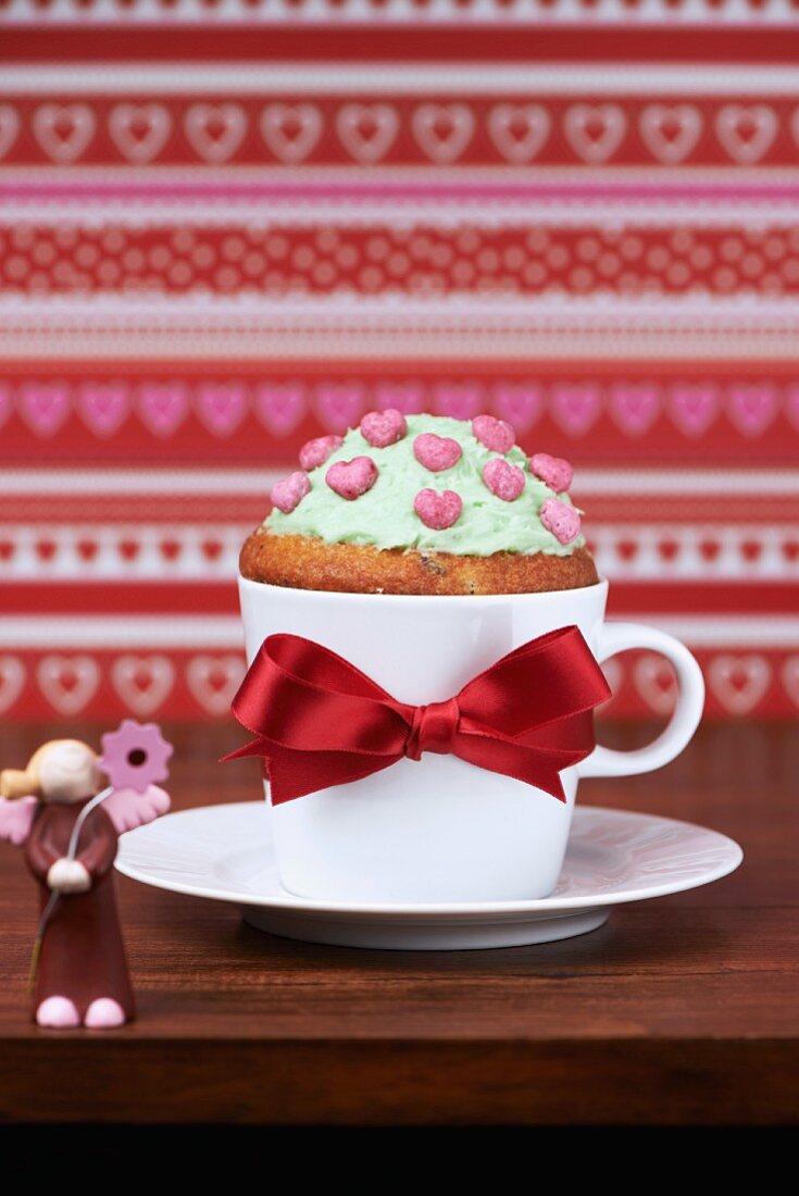 A guardian angel cupcake with butter cream and heart decorations in a coffee cup