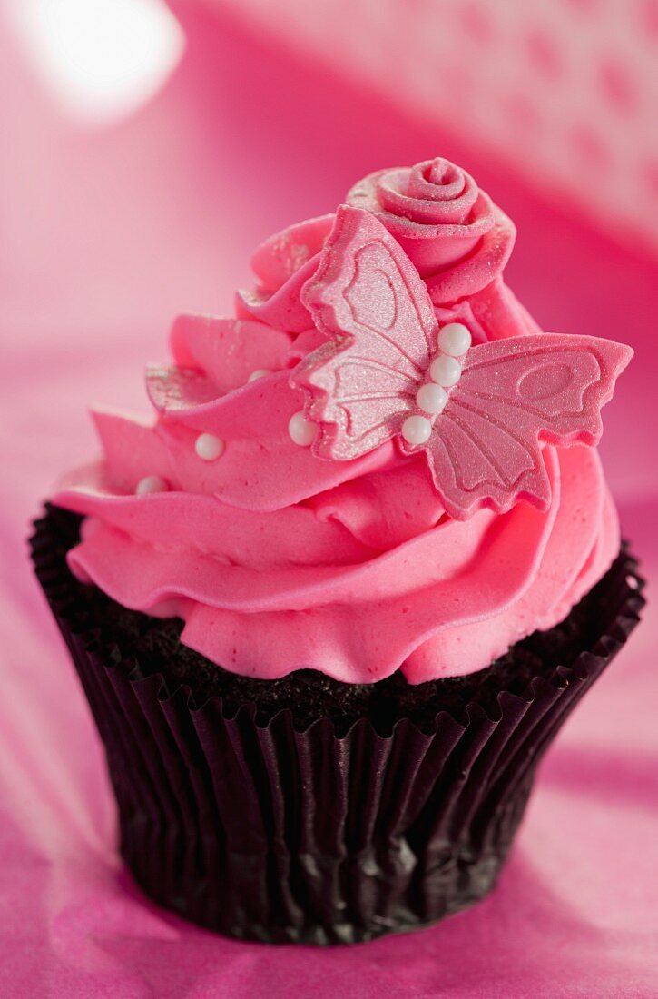 Chocolate cupcake with strawberry icing and a pink butterfly