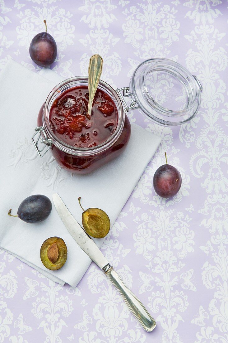 Stewed plums in a jar, with a silver spoon