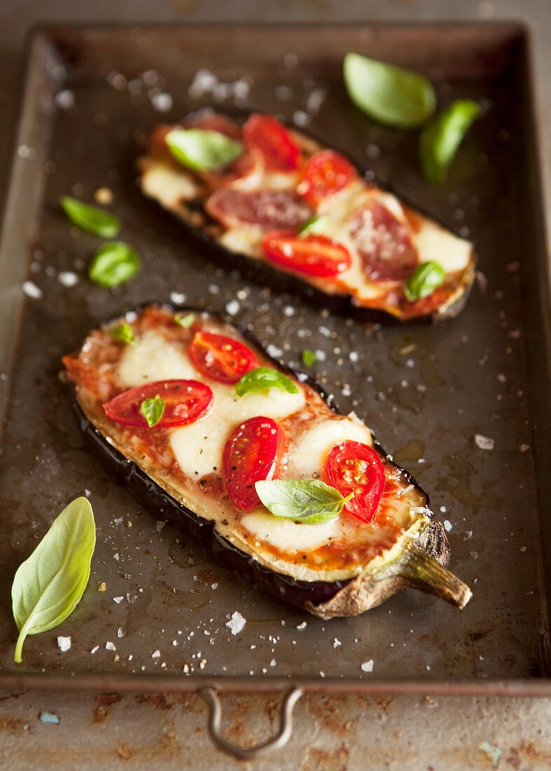 Aubergine halves topped with tomatoes and cheese and baked