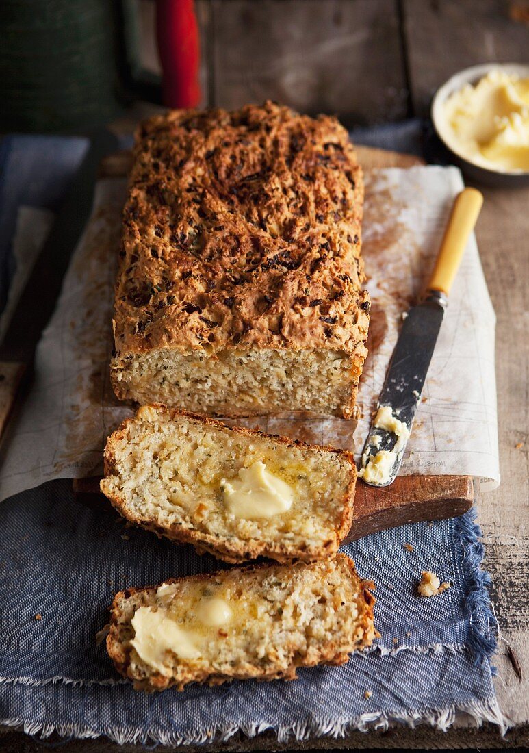 A loaf of onion, cheese and herb bread, partly sliced