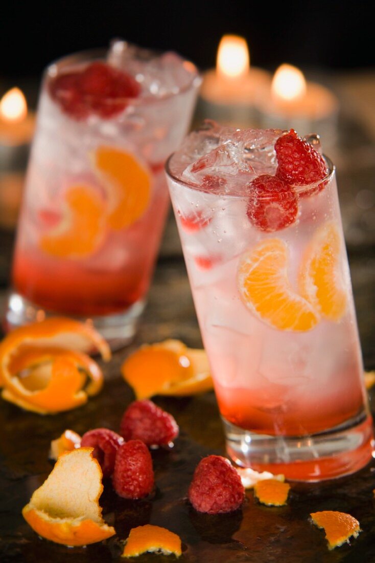Zwei fruchtige Cocktails mit Himbeeren und Mandarinen