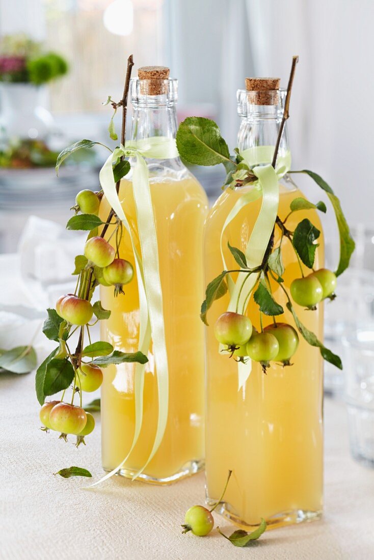 Apfelsaft in Flaschen, dekoriert mit Zieräpfelzweigen