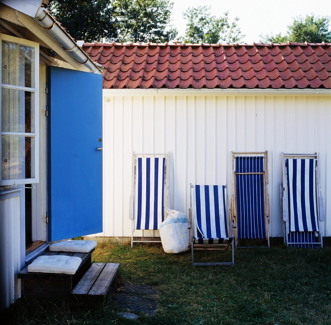 Weiß-blaue Liegestühle an weisser Holzwand