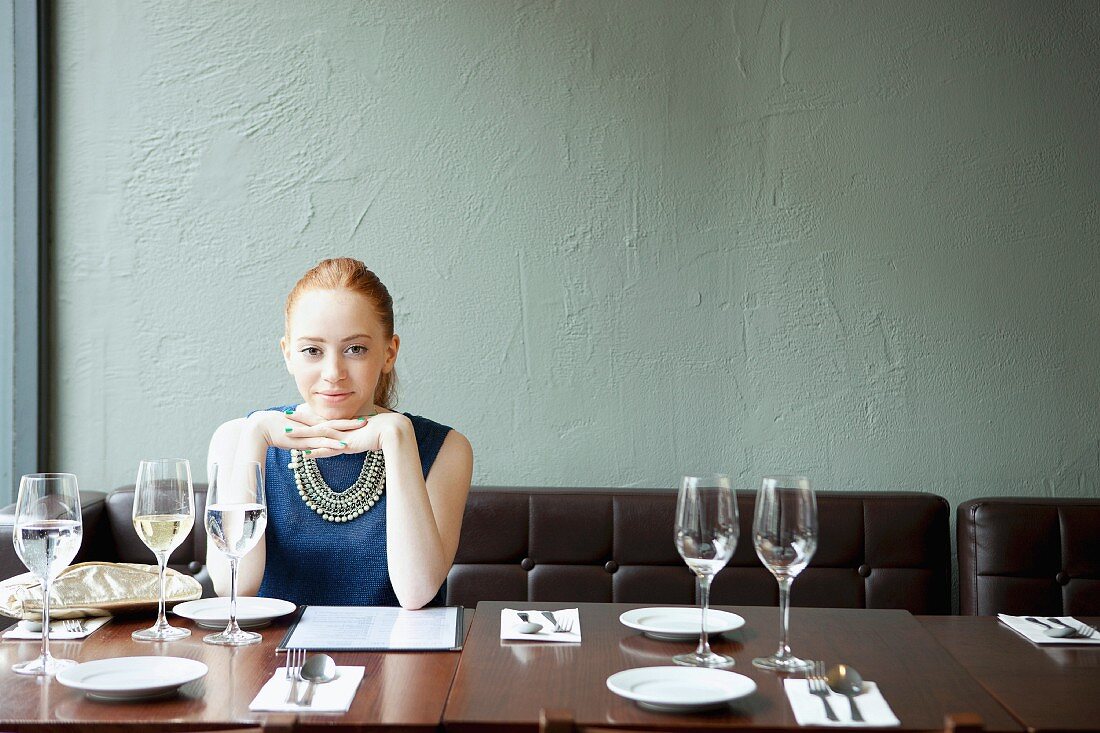 Junge Frau mit blauem Kleid in einem Restaurant sitzend