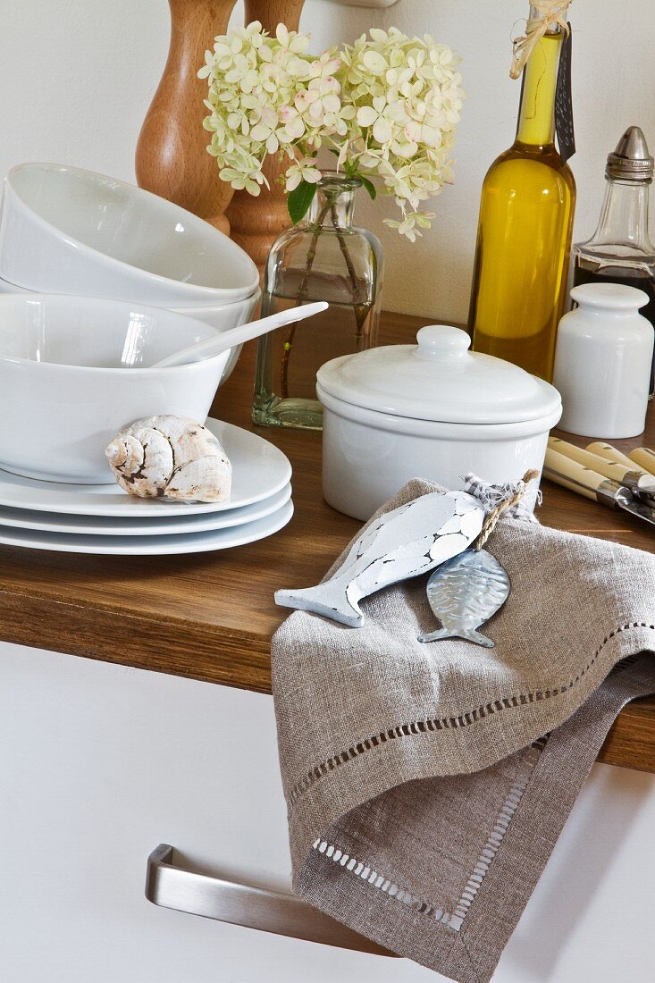 White china crockery, olive oil and hydrangeas on wooden surface