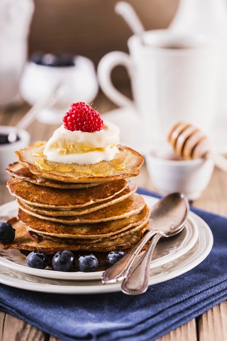 Stack of pancakes with cream, blueberry and raspberry