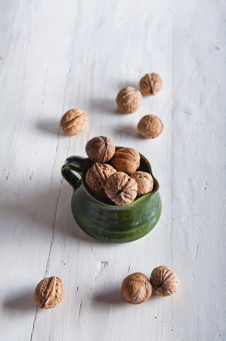 Walnuts in a ceramic jug and to one side