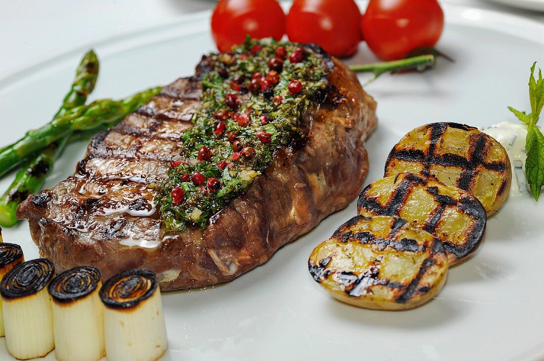 Grilled beef steak with herb butter and vegetables