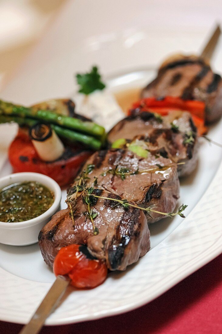 A barbecued pork skewer with tomatoes and thyme