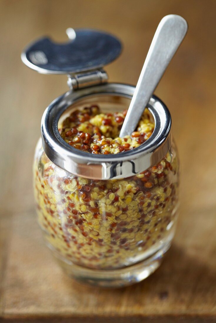 Coarse-grained mustard in a jar with a spoon