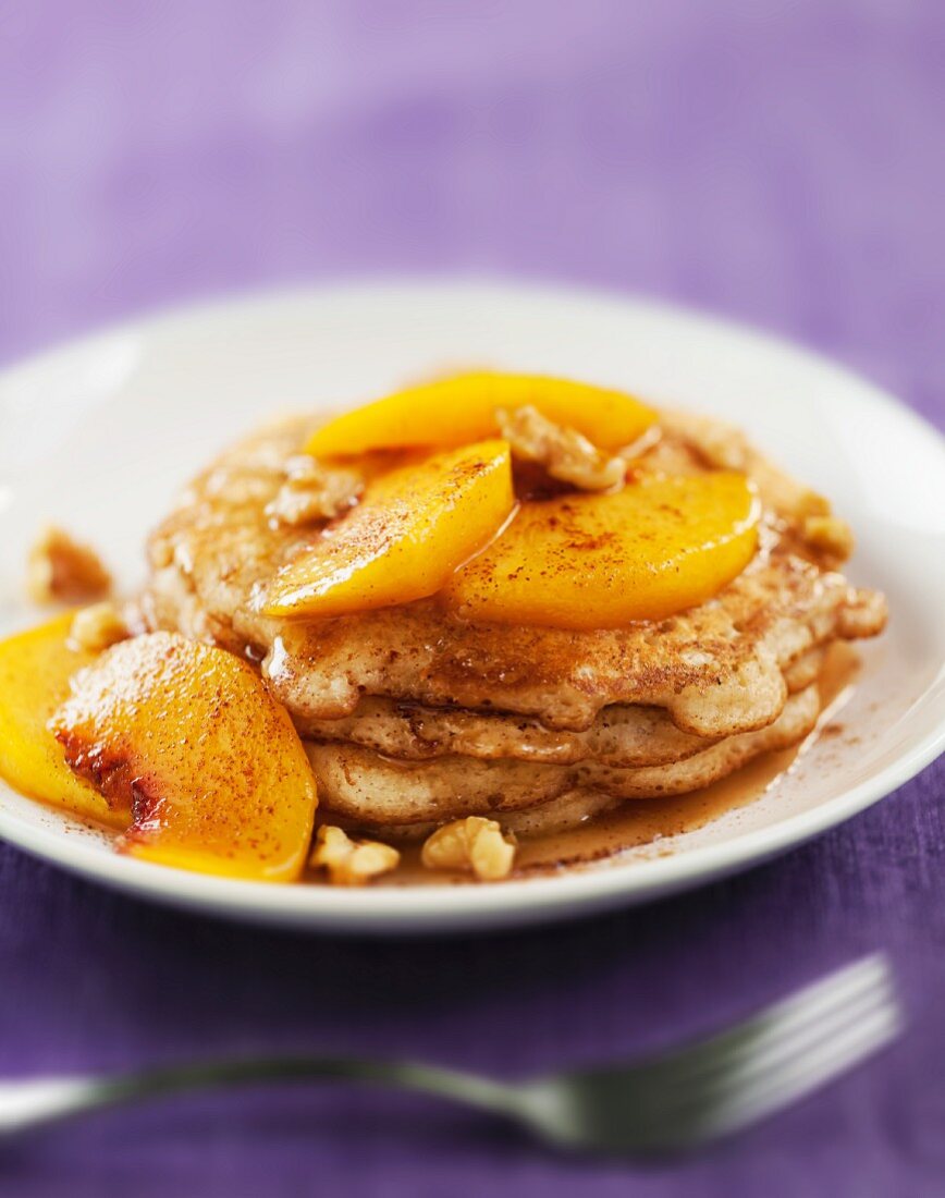 Pancakes covered with peach compote and walnuts