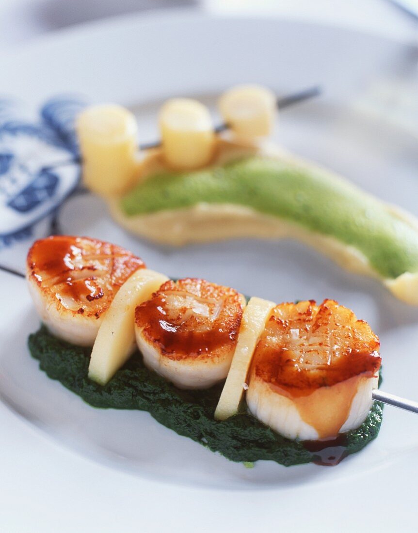 A skewer of scallops on a bed of spinach