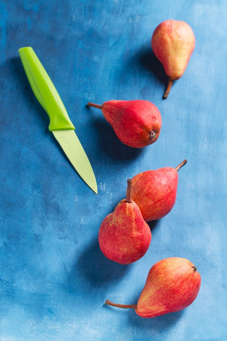 Red Williams pears on a blue surface, with a knife
