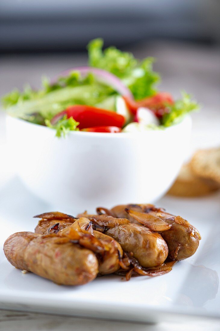 Fried sausages with onions and salad