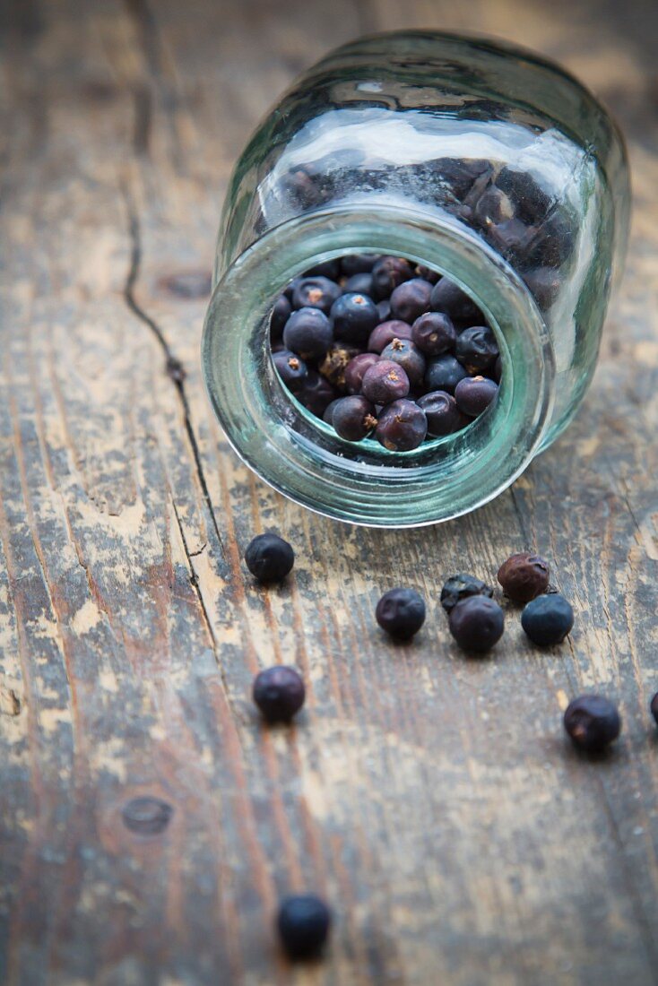 Juniper berries in an overturned jar on a wooden table