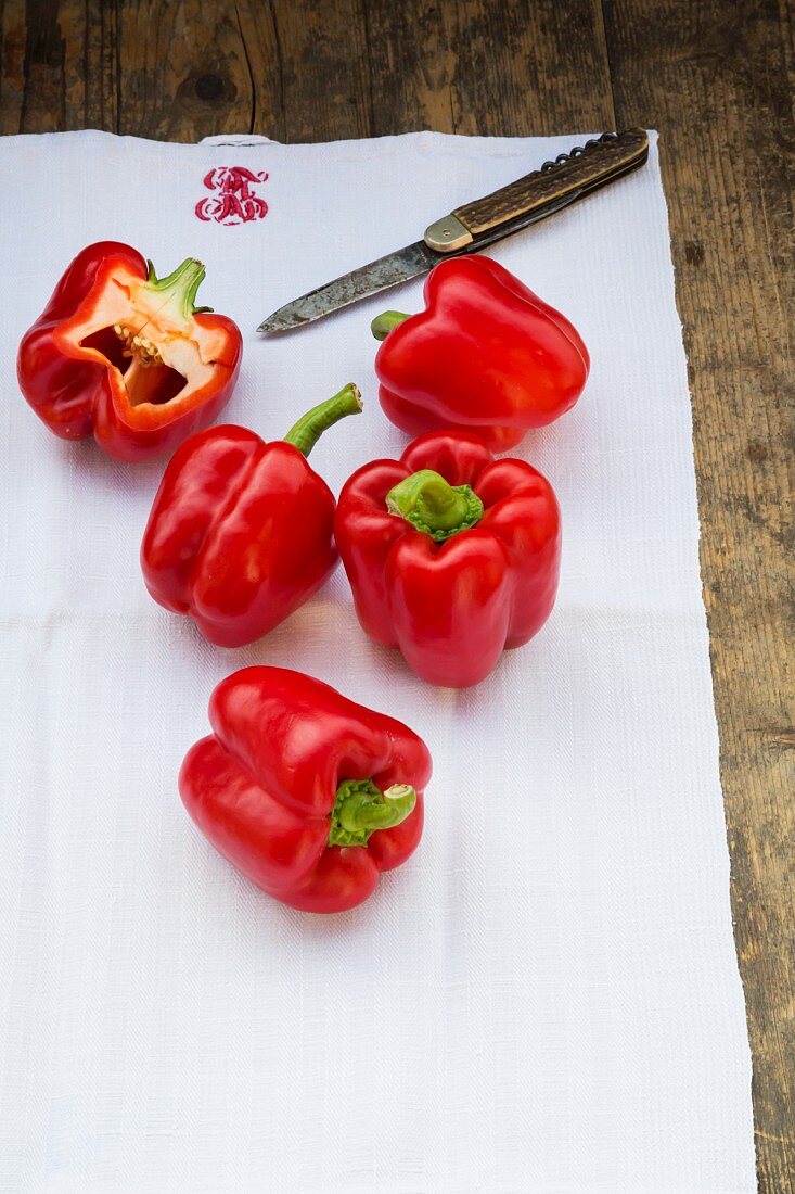 Red peppers on a tea towel with a knife