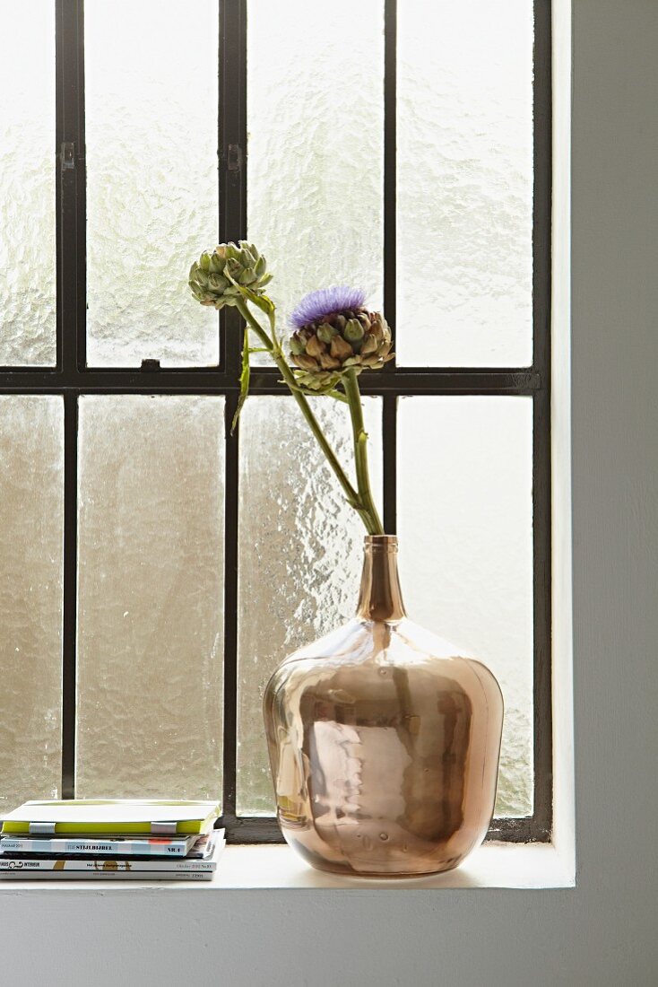 Dried artichoke flowers in shiny vase