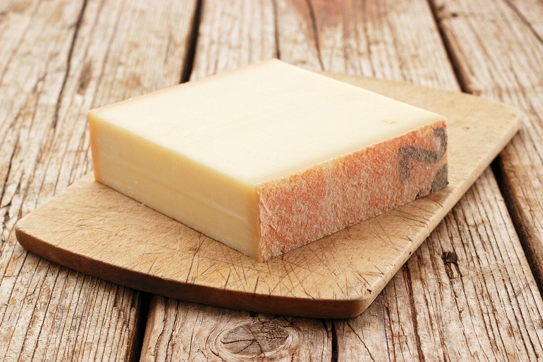A chunk of Gruyère cheese on a chopping board