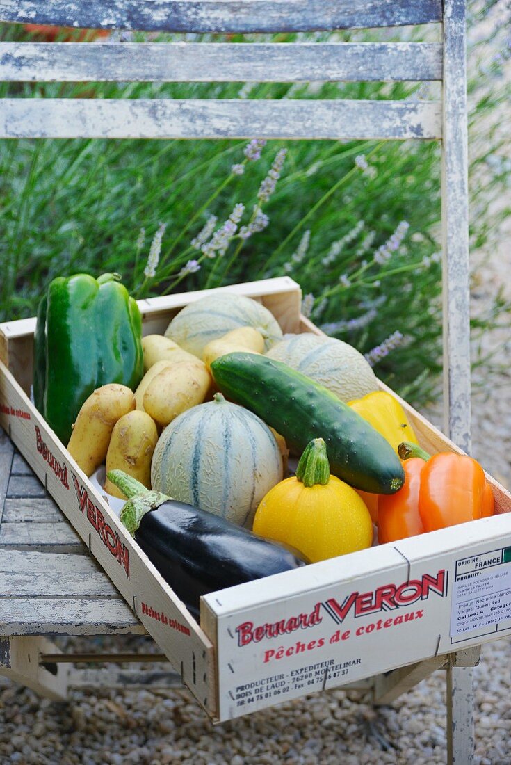 A wooden crate of vegetables and melons