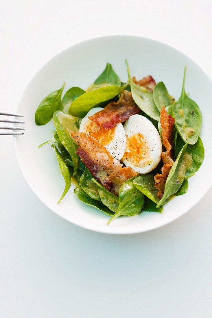Spinach salad with bacon and a boiled egg