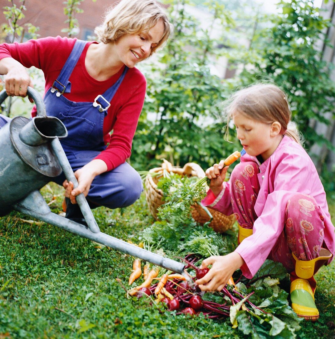 Mutter und Tochter mit frisch geerntetem Gemüse