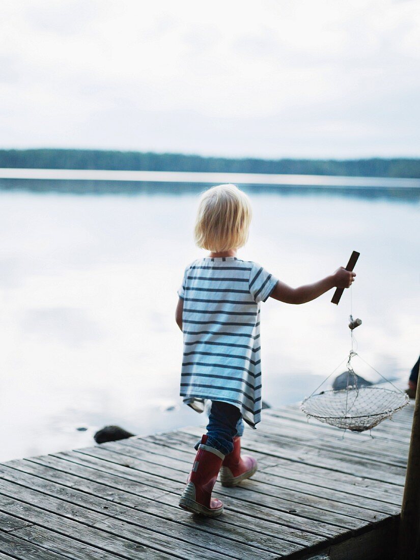 Girl walking on jetty carrying fishing net