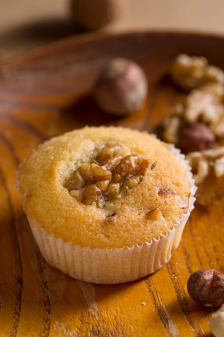 A muffin with nuts on a wooden plate
