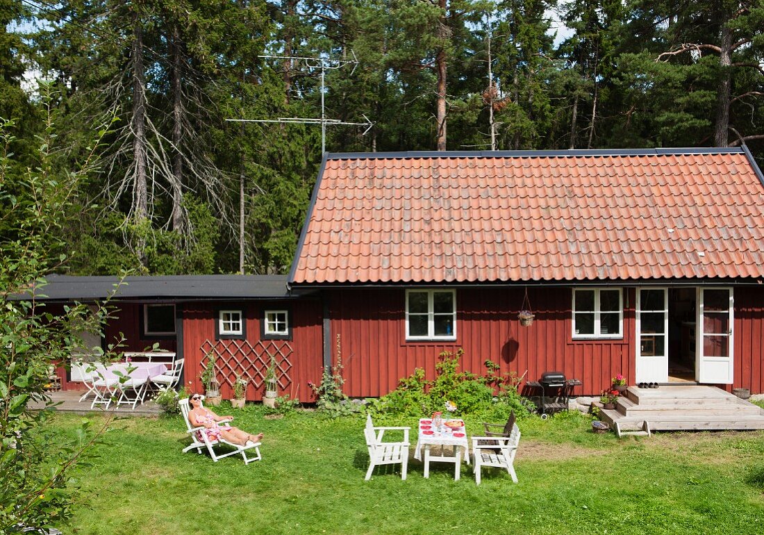Woman in lounger outside holiday cottage (Södermanland, Sweden)