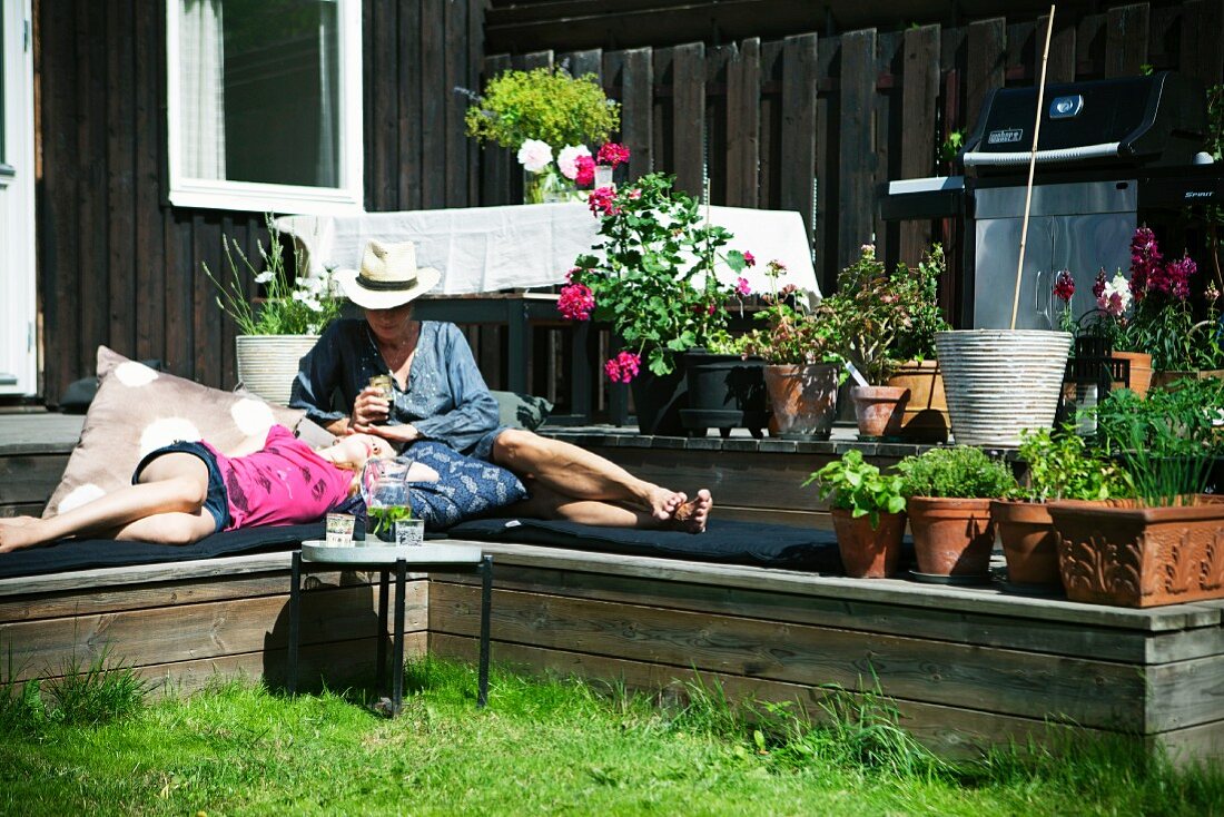 Mother and daughter relaxing in terrace steps in garden