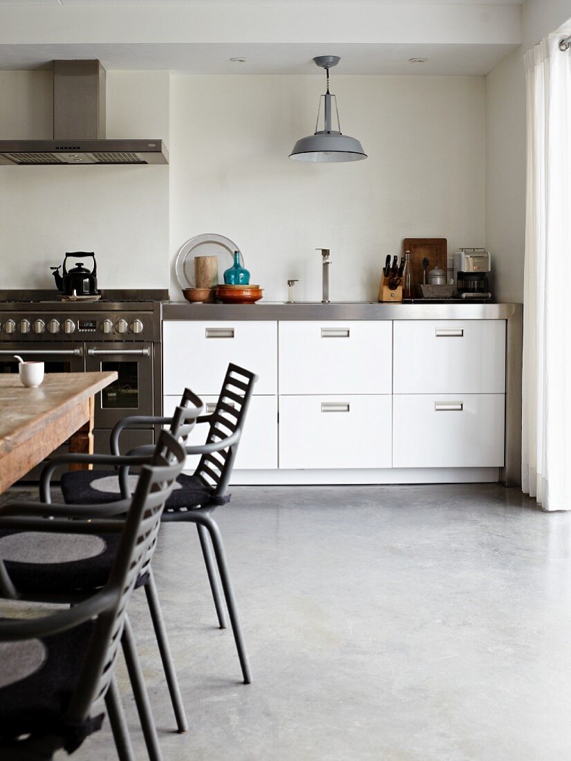 View from dining area to kitchen counter with stainless steel appliances and white drawer units