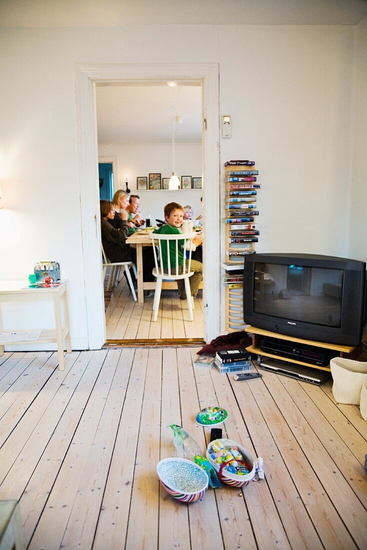 Blick durch Wohnraum mit Fernseher auf Familie am Esstisch