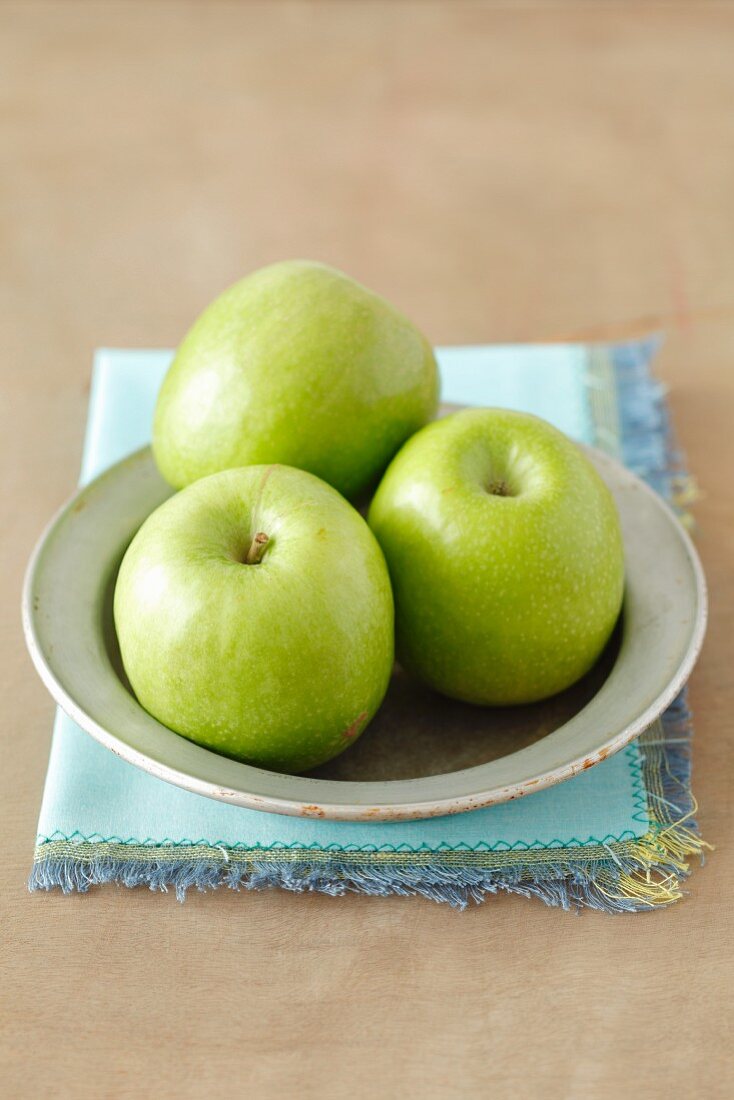 Drei grüne Äpfel auf Teller