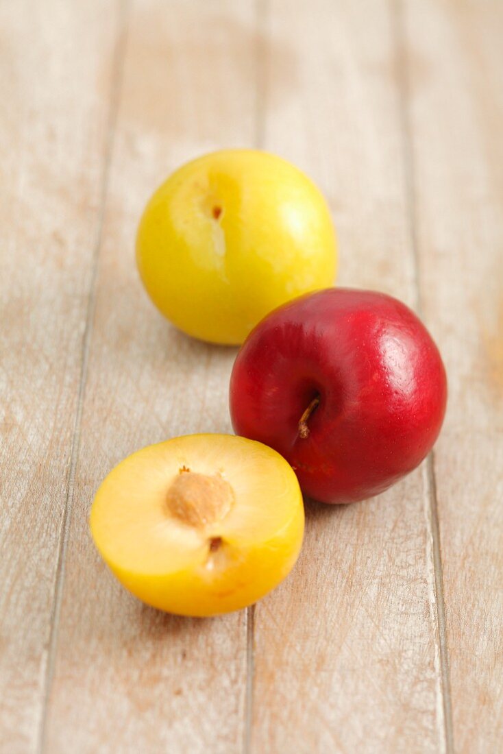 Fresh plums (yellow and red) on a wooden surface