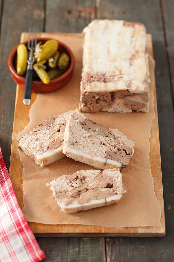 Pate mit Hähnchenleber, angeschnitten, Essiggurken im Schälchen