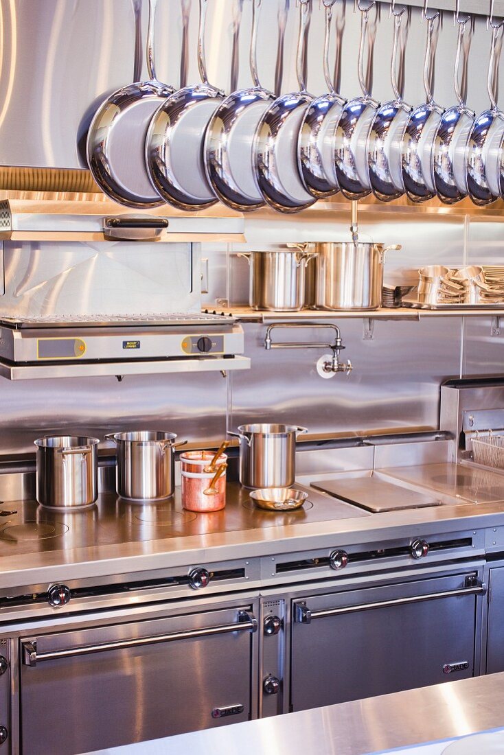 A Clean Professional Kitchen with Hanging Pans and Pots in the Background